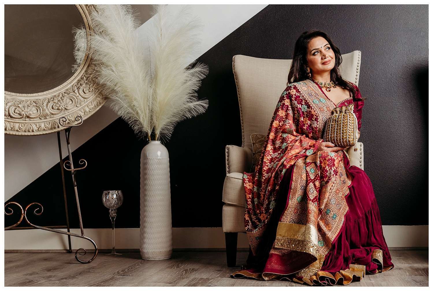 Model wearing luxurious Indian formal couture by Ensemble by Monika, featuring intricate embroidery and rich fabrics, posing gracefully in a minimalist setting during a branding shoot for weddings and special events.