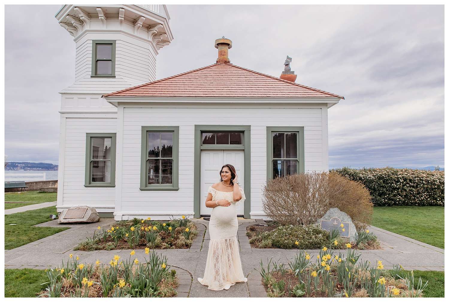 Pregnant woman at Mukilteo Lighthouse Beach during golden hour, wearing a cream lace maternity gown in soft shoreline poses and a teal fitted maternity dress with a long flowing train blowing in the ocean breeze, with the lighthouse and sunset in the background.