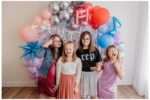 Children with Down syndrome dressed in colorful, sparkly outfits inspired by Taylor Swift’s Eras Tour, posing joyfully with microphones, sunglasses, and themed props in a bright, glittery setup at a downtown Everett photo studio for World Down Syndrome Day mini sessions.