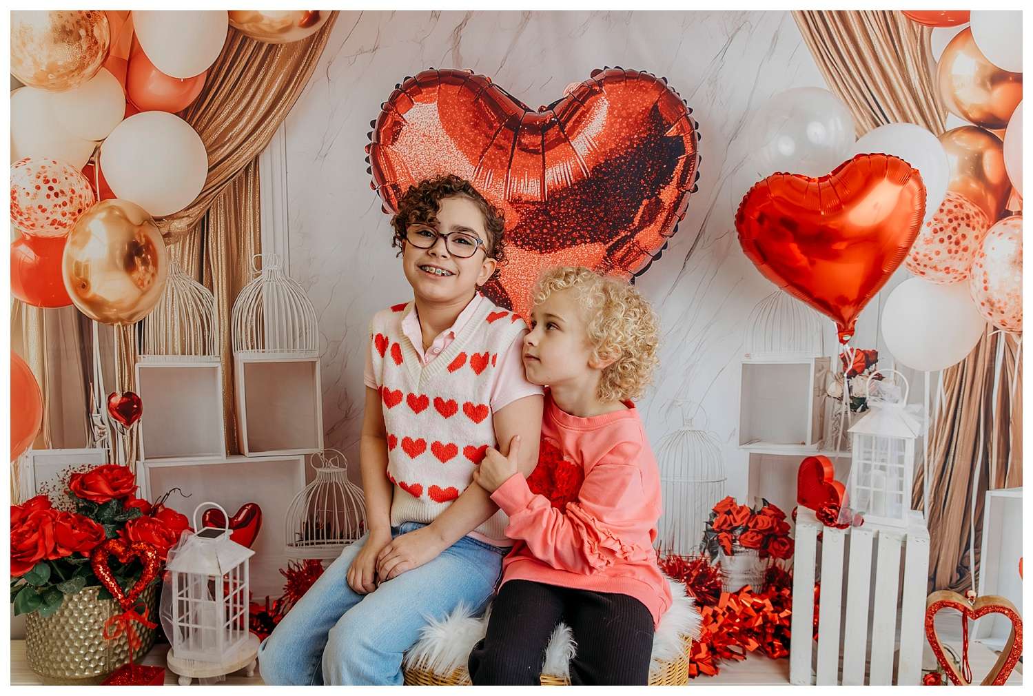 Valentine’s mini photo session in a downtown Everett studio featuring a festive heart-shaped balloon backdrop, with clients posing joyfully in romantic and playful outfits, surrounded by red, pink, and white decorations.