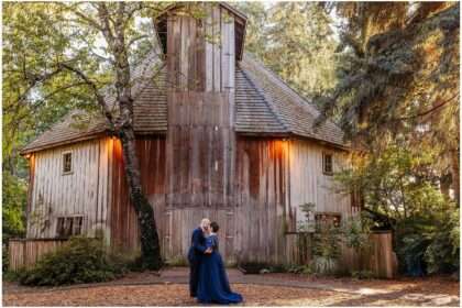 Couple standing together in front of a rustic wooden barn at McMenamins Cornelius Pass Roadhouse in Hillsboro, Oregon, surrounded by trees and warm October sunlight.