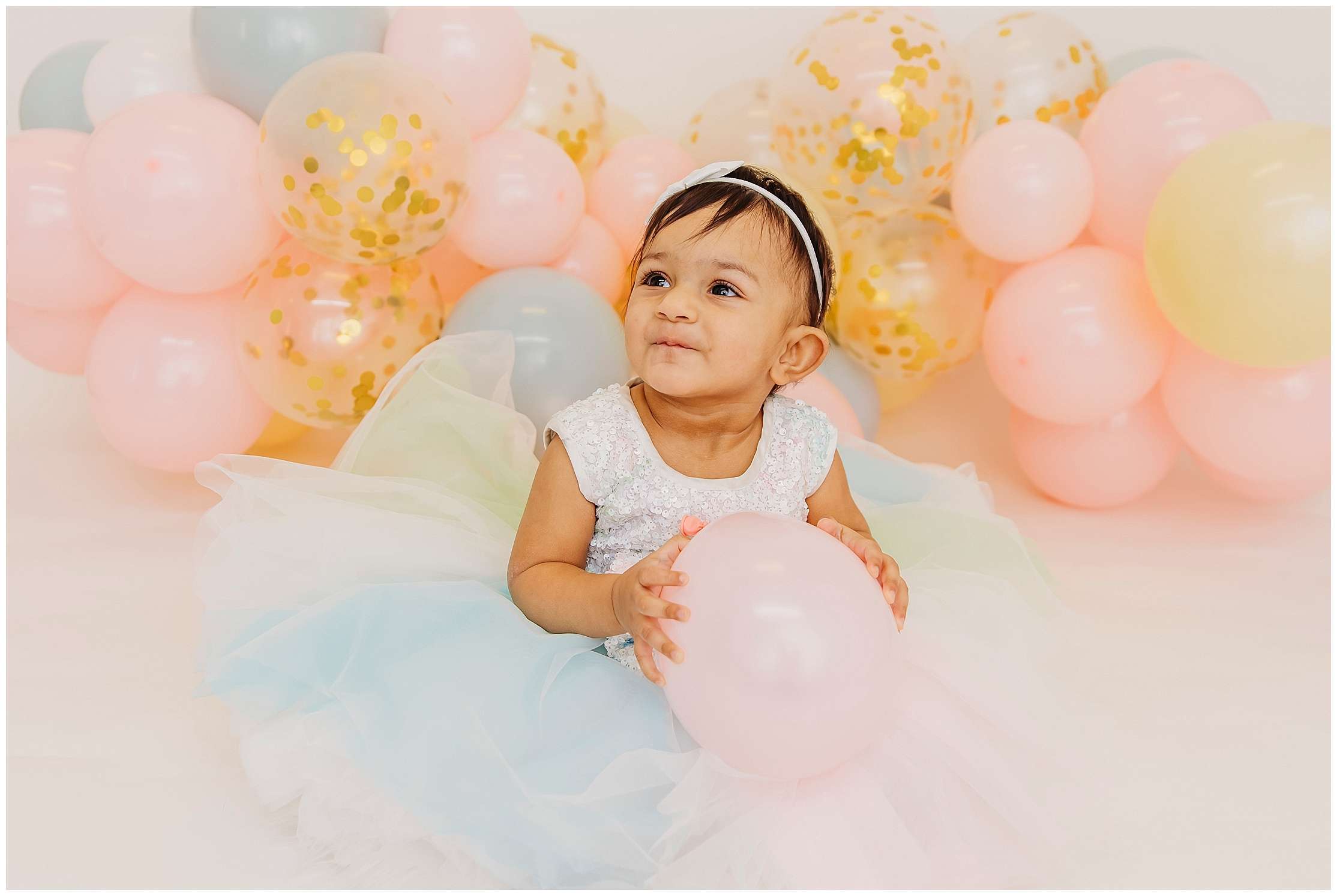Avya’s 1st birthday family photos in a downtown Everett studio with colorful balloons, capturing joyful family smiles and a baby celebrating her first birthday.