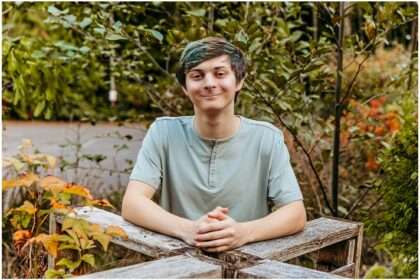 High school senior boy posing outdoors at McCollum Park with natural greenery background during simple casual senior photo session
