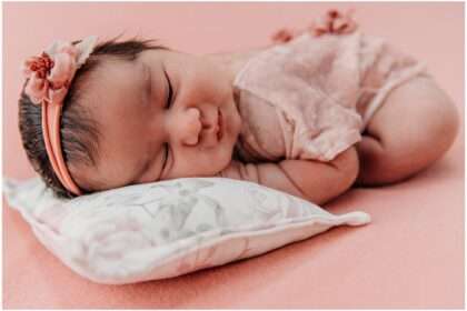 7-day-old newborn baby girl Eliana wrapped in a soft pink swaddle holding a small teddy bear during her newborn mini session in studio.