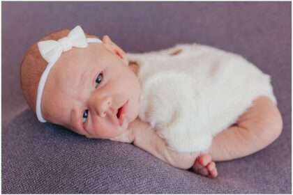 Newborn baby girl Elliana posed in a soft cream wrap with a white bow during her Downtown Everett studio newborn session.
