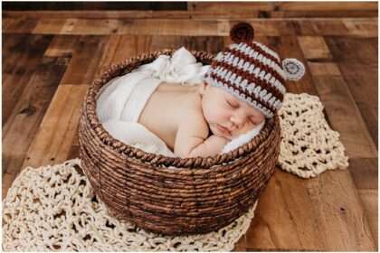 Two-month-old baby Oliver sleeping in a woven basket wearing a knit striped hat during a full newborn session at a Downtown Everett photography studio.