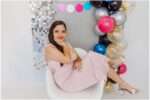 Teen girl posing in a pink sparkly dress during a colorful 15th birthday studio portrait session with bright balloons and a silver disco backdrop in Downtown Everett.